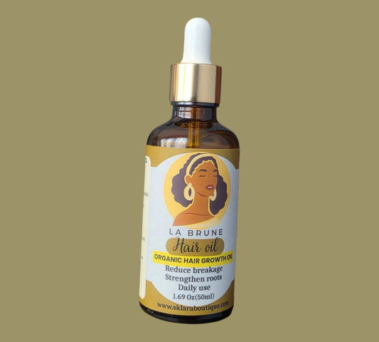 Bottle of La Brune hair oil with a dropper on a beige background